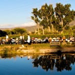 People gather around a dinner table with Mt Lamborn in the background for a farm-to-table dinner in Paonia.
